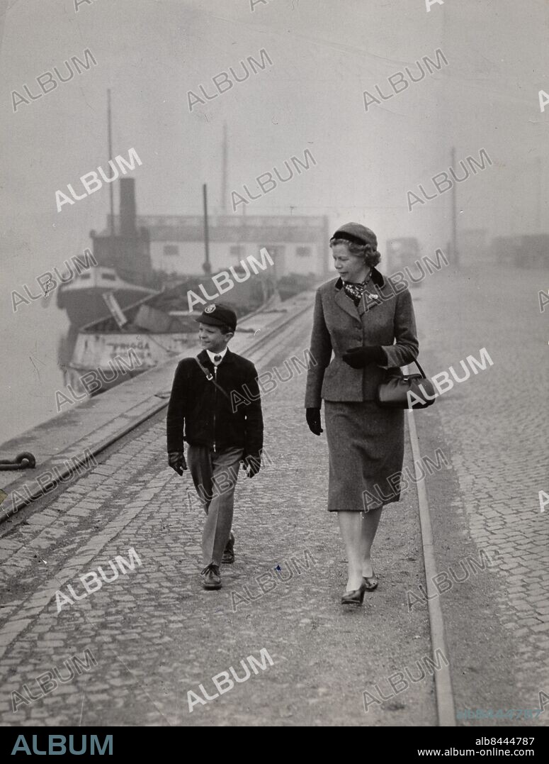 Kronprins Carl Gustaf vid en stilla morgonpromenad på Skeppsbron med Fröken Ingrid "Nenne" Björnberg på väg till Broms skola i Stockholm 1956. Foto: Text & Bilder / SVT / Kod: 5600.