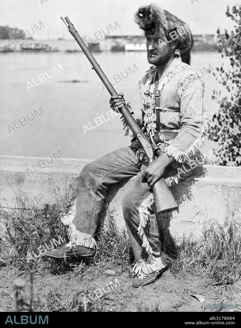 United States:  c. 1928 A man wearing a Davy Crockett outfit with a coonskin cap and a musket.   © Underwood Archives / The Image Works.