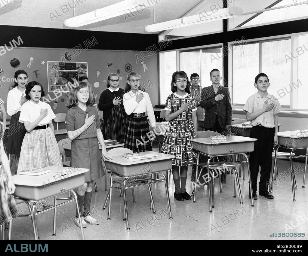 Students saluting the American flag in a classroom in 1957. The Pledge of Allegiance is a solemn vow of loyalty and support for the country. "I pledge allegiance to the flag of the United States of America, and to the republic for which it stands, one nation under God, indivisible, with liberty and justice for all." The Pledge of Allegiance first appeared in 1892 in a children's magazine. The phrase under God, added in 1954, has inspired heated debate over the separation of church and state. Swearing of the Pledge is accompanied by a salute. An early version of the salute, adopted in 1892, was known as the Bellamy salute. It started with the hand outstretched toward the flag, palm down, and ended with the palm up. Because of the similarity between the Bellamy salute and the Nazi salute, developed later, the United States Congress instituted the hand-over-the-heart gesture as the salute to be rendered by civilians during the Pledge of Allegiance and the national anthem in the United States, instead of the Bellamy salute. Removal of the Bellamy salute occurred on December 22, 1942, when Congress amended the Flag Code language first passed into law on June 22, 1942.