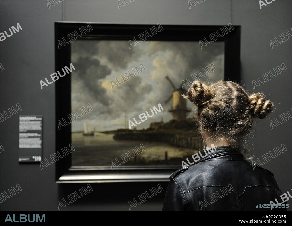 Muchacha observando el cuadro de JACOB RUYSDAEL (1628-1682), "El Molino de Wijk bij Duurstede", 1670. Rijksmuseum. Amsterdam. Paises Bajos.