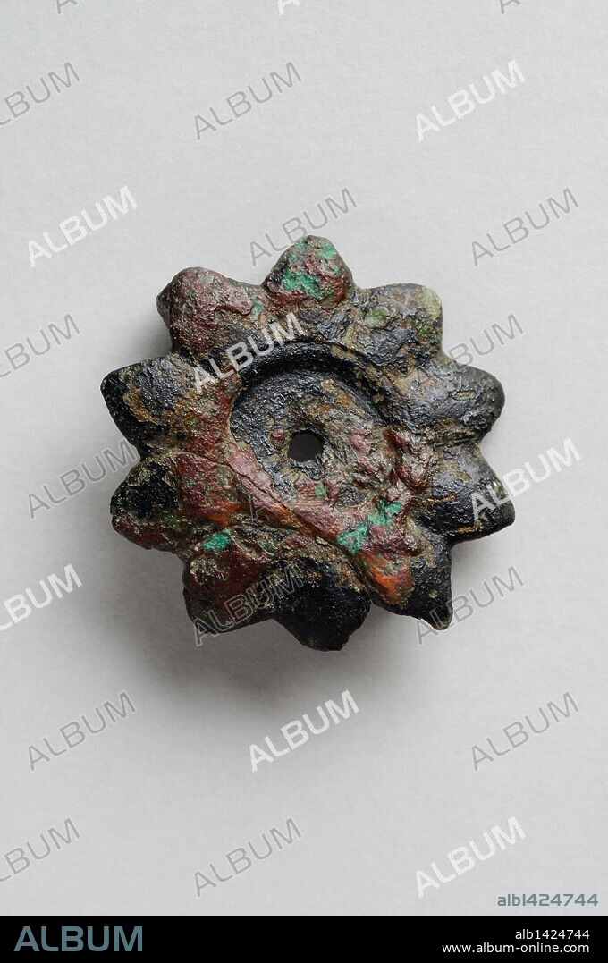 Fíbula de bronce en forma de estrella de diez puntas con circulo interior. Diámetro 2, 6 cm Grosor 0, 15 cm . (Siglo III - V d.C ) Epoca romana , procedente de la " Villa del Val " - Yacimiento arqueológico de Complutum en Alcalá de Henares ( Madrid ). ESPAÑA.