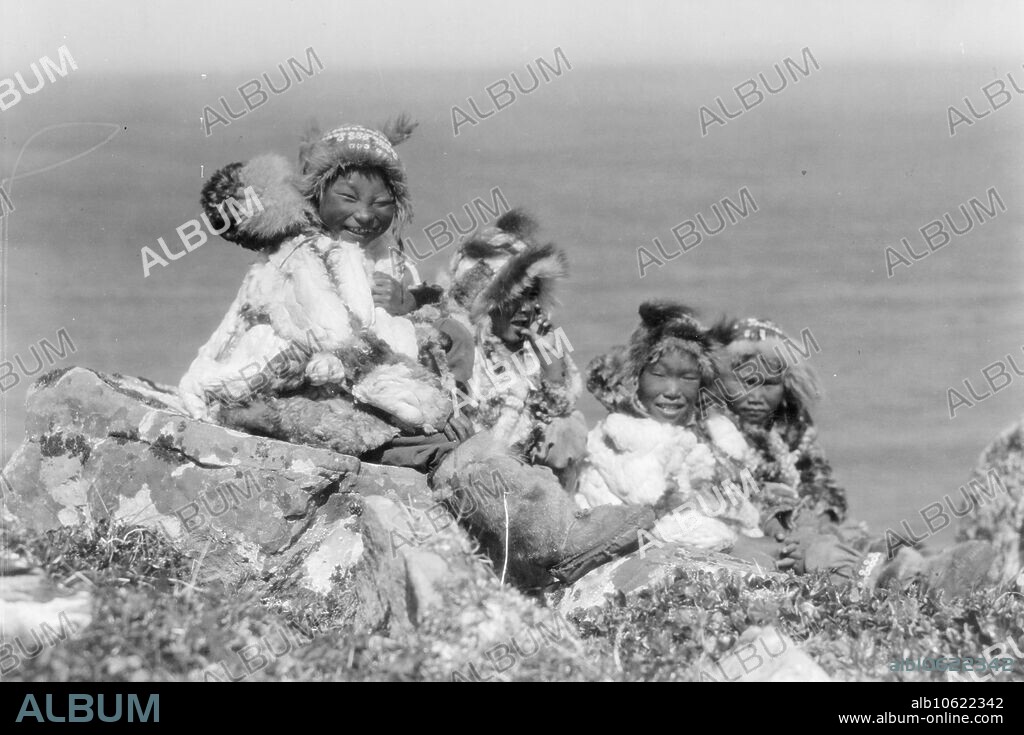 EDWARD SHERIFF CURTIS. Four Eskimo children, at edge of cliff, in holiday costume, Nunivak, Alaska, c1929.