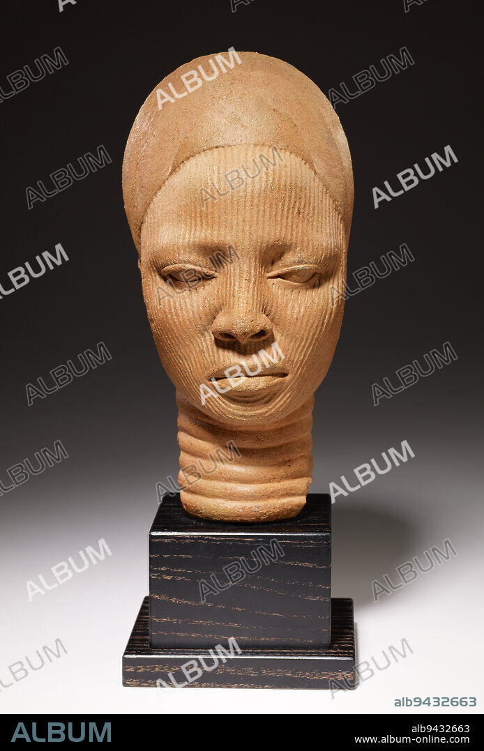 Shrine head, 12th-14th century, 12 1/4 x 5 3/4 x 7 1/4 in. (31.1 x 14.6 x 18.4 cm), Terracotta, Nigeria, 12th-14th century, This heads tranquil demeanor and introspective gaze express what the Yoruba peoples consider a persons inner virtue. It is a memorial portrait head that comes from the royal city of Ife in western Nigeria, a center of economic, religious, and political power between 1100 and 1400. Ancient Yoruba artists made heads in bronze and terracotta that were part of complete figures or, like here, freestanding. The vertical lines covering the womans face either reflect the traditional scarification designs used in the Ife kingdom or represent the veil worn by members of the royal family.