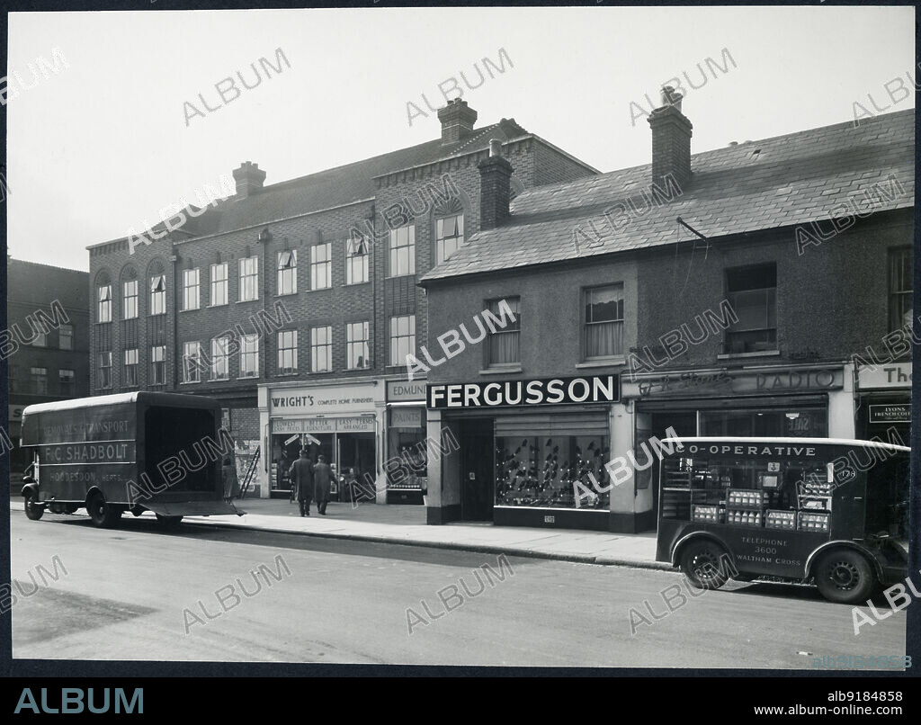 HEALEY AND BAKER. 117-119 High Street, Waltham Cross, Broxbourne, Hertfordshire, 1948-1960. View from the north-east of 117-119 High Street, showing the shop fronts, with a removal lorry and a milk float on the road.