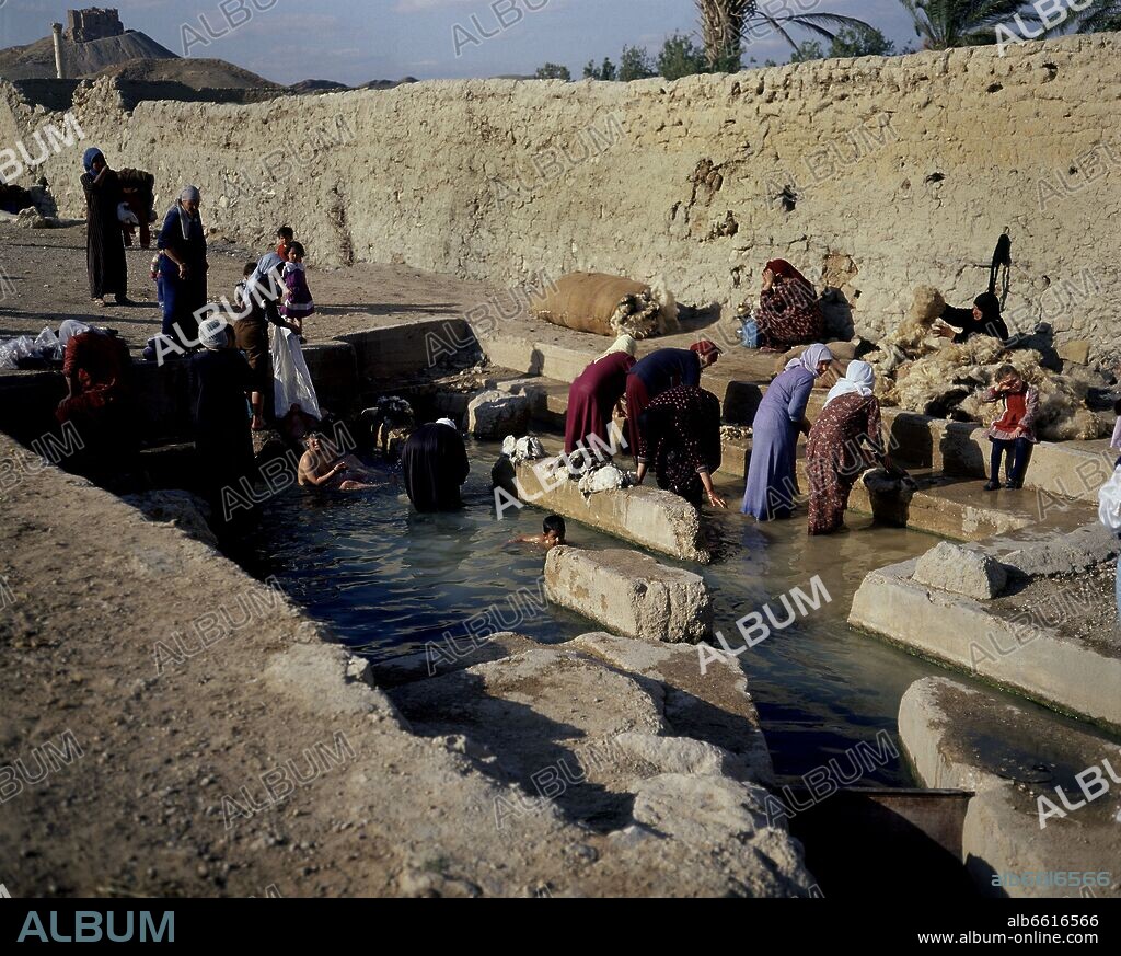 MUJERES Y NIÑOS BAÑANDOSE Y LAVANDO LANA EN UN LAVADERO NATURAL.