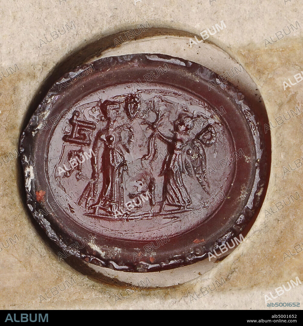 Demeter (to the right) has a number of ears of corn in the right hand and an unidentified object in the left hand (fruit bowl?). The goddess Nike (left) in a peplum with wings reaches a laurel wreath with ribbons to the head of Demeter. Around Demeter three letters, ground line., Gem, intaglio, ringstone, glass, Color: red, transparent, Shape: oval, lying, Machined: Maaskant-Kleibrink, M., Catalog of the engraved gems at the Royal Coin Cabinet, 1978 , p.60, fig.2, type F1. The edge at the front contains a groove around the performance, 13.5 x 16 mm. Thickness? mm., Italy, unknown, unknown, unknown.