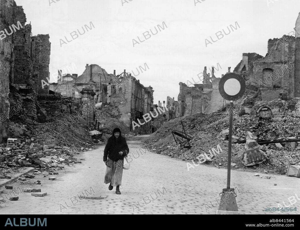Orig. bildtext... WARSAW 1946 - EUROPE'S GHOST CITY Warsaw, Poland. This aged polish woman, trudging alone on the cobblestoned streets through the ruins of Warsaw, is symbolic of the maelstrom of misrey and destruction suffered by the city of Warsaw during World War II. The city, with its population of 1,264,000, was first bombed by hordes of german planes in sept. 1939 when the germans first invaded Poland. The survivors, niw only a pitifully small remnant of the former population, are for the most part half-starved and ill-clad. Only the traffic sign here remains as a pitiful reminder of the days when traffic flowed busily through the main thoroughfares, days which the indominatable people of Warsaw say will come again. These are the first and exclusive photos of the ruins of Warsaw. Orig. bildtext... WARSZAWA - EUROPAS SPÖKSTAD. Denna åldriga polska kvinna på tröstlös vandring genom en av Warszawas ruingator kan vara en symbol för alla utarmade och hemlösa i det sönderslagna Europa, där Warszawa gör skäl för namnet spökstaden. Anm. Efterkrigstiden Skyltar Gatuskyltar CD131 sites: POLEN ;WARSZAWA.