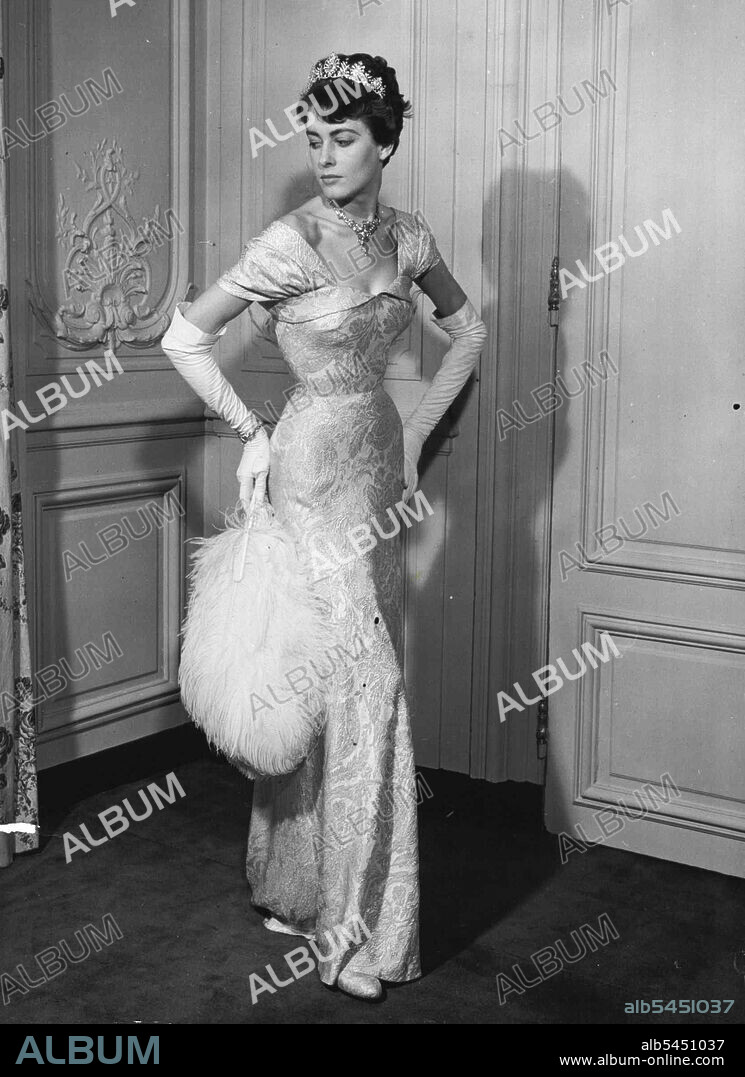 Moulded over the figure, Mattli's white and silver lame court dress falls into a graceful train at the back. The neckline is cuffed, with an epaulette sleeve effect. November 13, 1952.