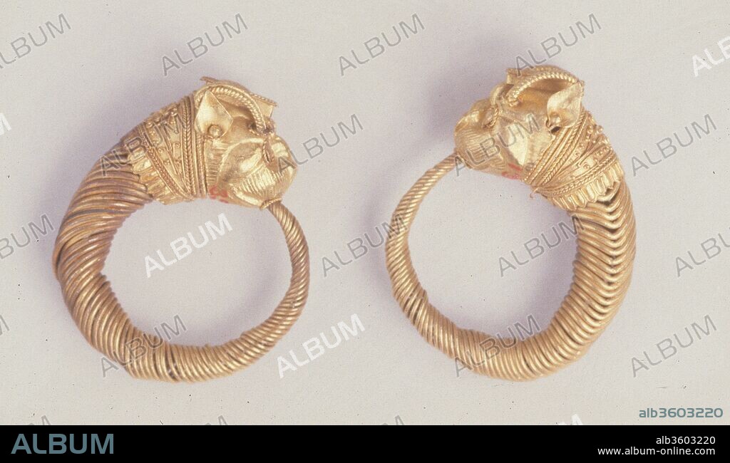 Earring with lion-griffin head terminal. Dimensions: As Worn: H. 2.3 × W. 2.2 cm (7/8 × 7/8 in.). Date: 4th-3rd century B.C..
Hoops formed of wound wire with animal head terminals are the commonest type of Hellenistic earring. The griffin is a mythical winged animal that could have an eagle head or a horned lion-head. The latter is the only sort found on Egyptian jewelry; it has been suggested that it was associated with the Macedonian dynasty, while the eagle griffin was associated with the Achamenid Persians.
The 'collar' behind the lion-griffin's head is decorated with granulation and filagree.