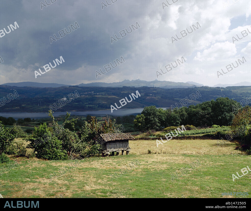 GALICIA. PAISAJE GALLEGO con un HORREO en las proximidades de la localidad de Santa Comba de Bande. Al fondo el EMBALSE DAS CONCHAS. Provincia de Ourense. España.