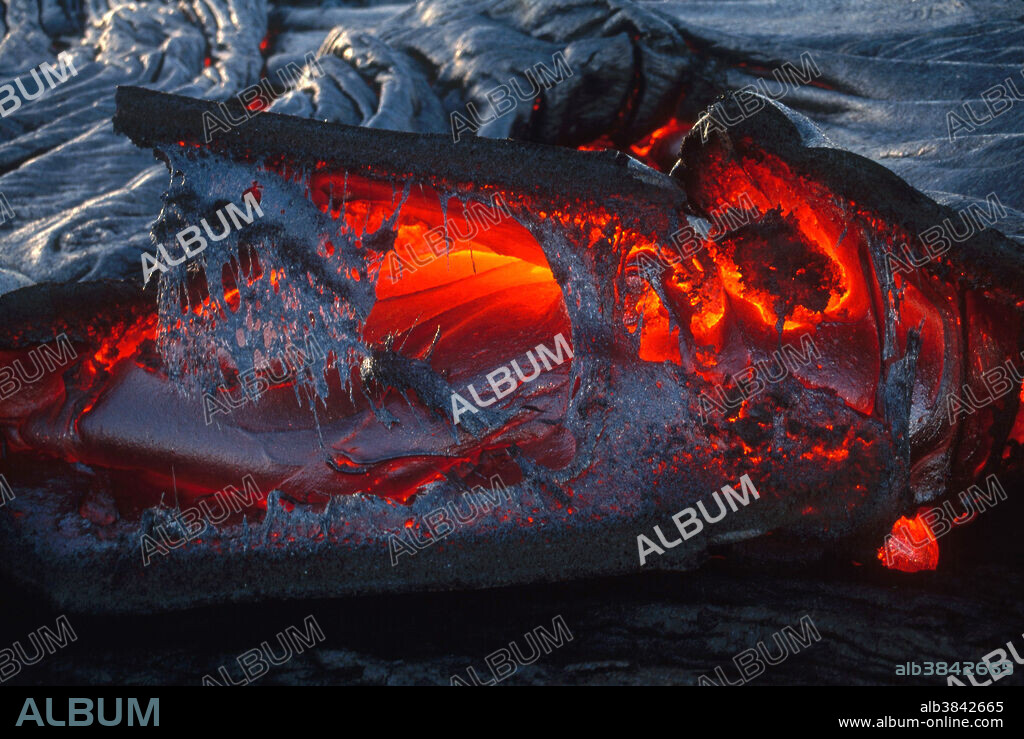 Pahoehoe lava (meaning smooth, unbroken lava, a basaltic lava with a smooth, billowing, undulating or ropy surface, due to the movement of very fluid lava under a congealing surface crust), plates with tongue of liquid lava, and fibrous net lava, from Hawaii's Kilauea volcano; November 2, 1999.