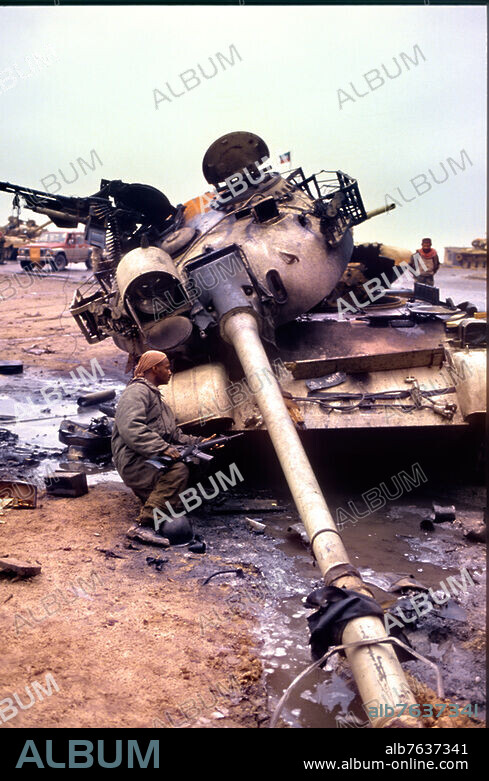 Guerre du Golfe (02.08.1990 - 28.02.1991) entre l'Irak et une coalition de 35 États, dirigée par les États-Unis à la suite de l'invasion et l'annexion du Koweït par l'Irak. Libération du Koweït par la coalition anti-irakienne. Un homme armé d'une mitraillette s'abrite derrière un char détruit. Photo, 1991.