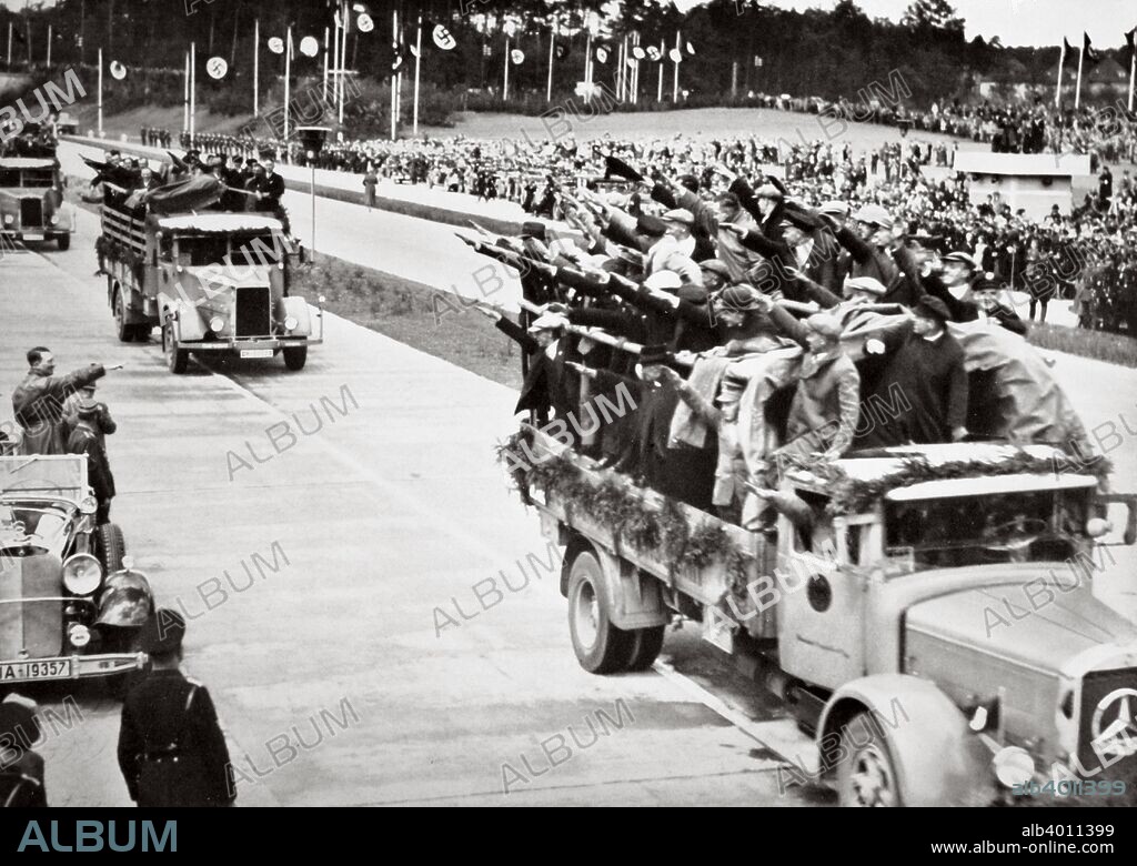 Labourers salute Hitler from packed trucks on a Nazi-built road, Germany, 1936. Hitler (1889-1945) ordered an ambitious programme of building the autobahn network soon after he came to power in 1933. The project not only improved Germany's transport infrastructure but also created 100,000 jobs and was a propaganda coup From Germany: The Olympic Year, published by Volk und Reich Verlag. (Berlin, 1936).