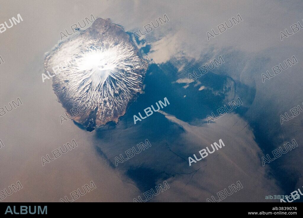 Atlasov Island, part of the The Kuril Island chain that extends from the Kamchatka Peninsula to Japan. This astronaut photograph, taken from the International Space Station (ISS) highlights Alaid Volcano, the northernmost and highest volcano in the chain (2,339 meters above sea level). The volcano rises 3000 meters from the floor of the Sea of Okhotsk, with the uppermost part of the volcano exposed as an island. (Note that the image is oriented so that north is to the lower left.) Volcanoes in the Kurils and similar island arcs in the Pacific "ring of fire," are fed by magma generated along the boundary between two tectonic plates, where one plate is being driven beneath the other (a process known as subduction). Alaid Volcano has been historically active, with the most recent confirmed explosive activity in 1996.