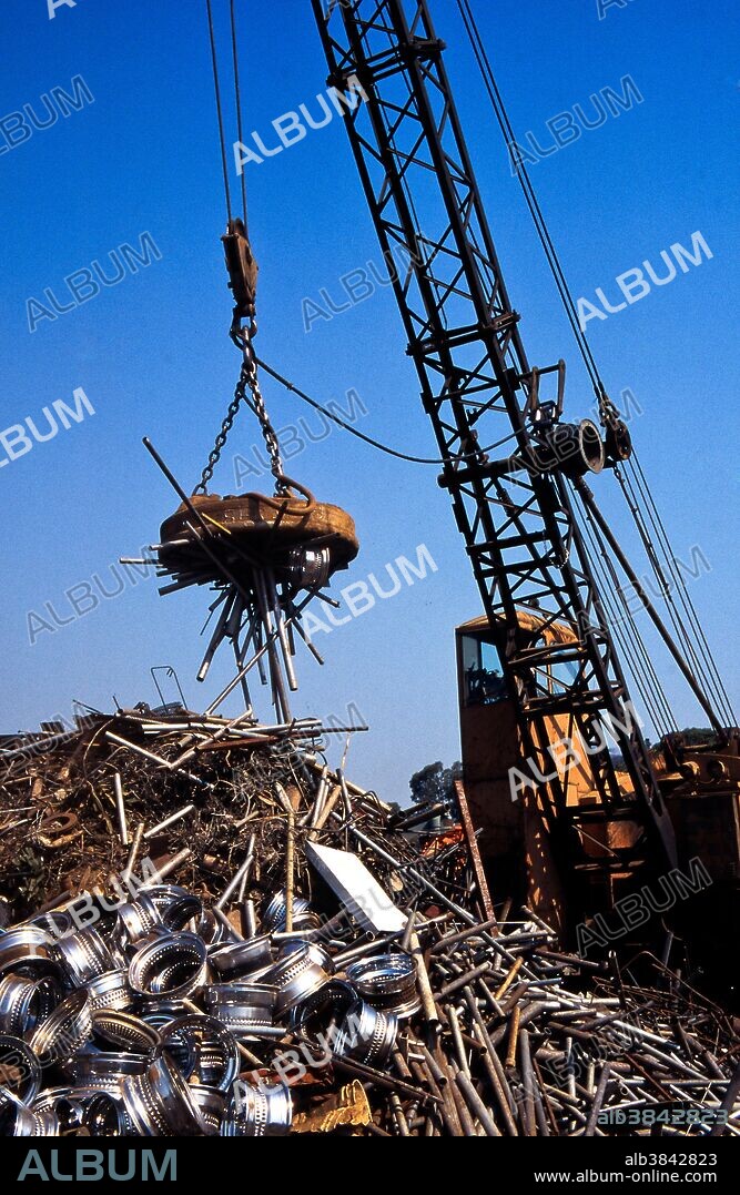 A giant crane-mounted electromagnet is used to move a pile of iron and steel items at a scrap yard in Carson, California.