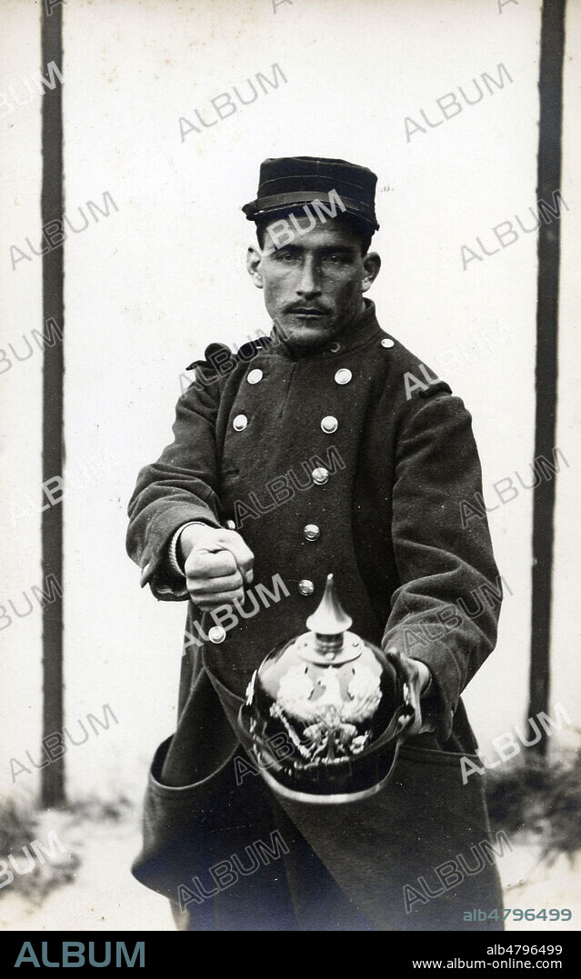 Soldat francais montrant un casque allemand en serrant le poing. Photographie anonyme pour une carte postale de la guerre 14-18. Credit : Collection IM/KHARBINE-TAPABOR.