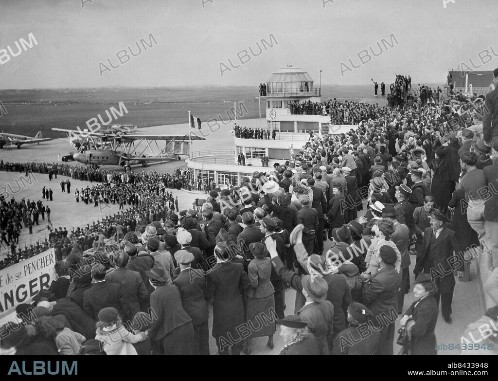 Orig. bildtext... PREMIER DALADIER RECEIVES WILD WELCOME UPON RETURN FROM MUNICH AFTER SUCCESSFUL FOUR POWER PEACE CONFERENCE. Photo shows - Scene at Le Bourget upon the arrival of Premier Daladier where thousands were on hand to greet him. Paris Sept. 30th 1938. Anm. E Daladier, 1884-1970, fransk politiker, regeringschef jan-okt 1933, jan-feb 1934, april 1938-mars 1940. 1938 ingicks ett avtal, Münchenöverenskommelsen, mellan Tyskland, Storbritannien, Frankrike och Italien, som bl a innebar att Tjeckoslovakien skulle överlämna det tyskspråkiga Sudetlandet till Tyskland. Hemkomst Resenärer Trängsel Vinka CD634 persons: EDOUARD DALADIER* sites: PARIS;FRANKRIKE.