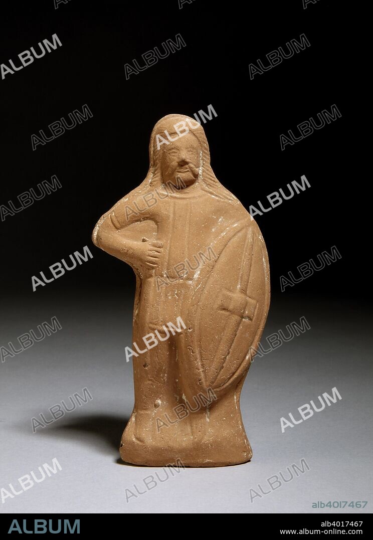 Terracotta statuette of a barbarian warrior, Roman. Figure has long hair flowing over his shoulders, a beard and long, drooping moustaches; he wears a short-sleeved tunic, trousers and shoes; in his right hand, he holds a sword by his side; against his left side, he holds an oval shield with raised centre. Dimensions: height: 17 cm.
