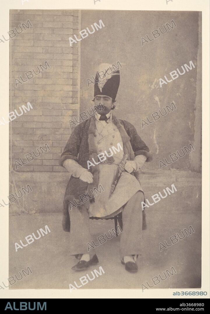 Naser al-Din Shah. Artist: Possibly by Luigi Pesce (Italian, 1818-1891). Dimensions: Image: 19.5 x 13.5 cm (7 11/16 x 5 5/16 in.). Person in Photograph: Person in photograph Naser od-Din Shah (Iranian, Tehran 1831-1896 Tehran). Date: ca. 1855-58.
This photograph demonstrates what the medium brought to the art of portraiture-a certain personal and candid quality. Here, although Nasir al-Din Shah (r. 1848-96) appears in a costume he wears in more formal portraits, the pose and expression adopted in this photograph are more relaxed. He is shown outdoors, seated rather than standing, and leaning back in a chair rather than sitting upright. One hand lies casually in his lap, the other is placed on his hip. This type of photograph reflects Nasir al-Din's interest in recording the private, daily life of his household in addition to using photography to capture the official aspects of the court. He was a photographer himself and among his favorite subjects were members of his family and personal harem.