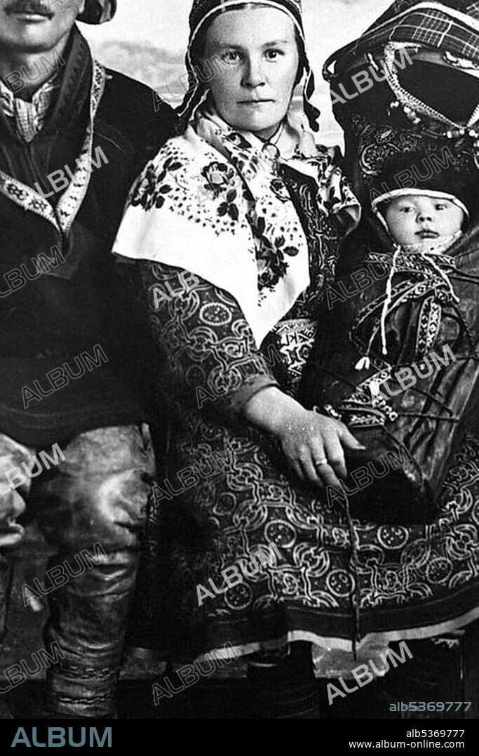 Sami wearing traditional clothing, holding a baby, historic picture from about 1920, Sweden, Scandinavia, Europe