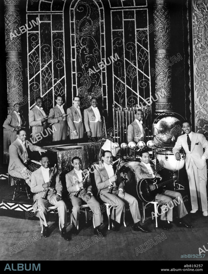 American bandleader and composer Duke Ellington posing with his orchestra on a stage at the Regal Theatre, Chicago. L-R includes: Freddy Jenkins, Wellman Braud, Cotie Williams, Harry Carney, Juan Tizol, Johnny Hodges, Tricky Sam Nanton, Barney Bigard, Sonny Greer, Fred Guy and Ellington. 1931.