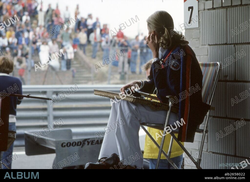 Barbra Peterson, racing driver Ronnie's wife, in the pits with Brabham wing by the lady's feet. 1976.