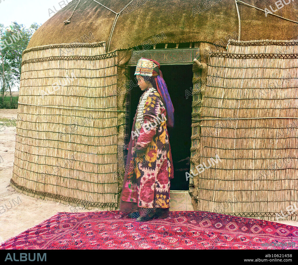 SERGEY MIKHAYLOVICH PROKUDIN-GORSKY. Full-length profile portrait of a woman, possibly Turkman or Kirgiz, standing on a carpet at the entrance to a yurt, dressed in traditional clothing and jewelry, between 1905 and 1915. Ethnic Diversity: Profile of a Nomad. In this portrait, Prokudin-Gorksii captures the traditional dress, jewelry, and hairstyle of an Uzbek woman. A yurt is a portable tent used for housing by the nomadic peoples of Central Asia. After conquering Turkestan in the mid 1800s, the Russian government exerted strong pressure on the nomadic peoples to adopt a sedentary lifestyle and settle permanently in villages, towns, and cities. Russian chemist and photographer Sergey Prokudin-Gorsky (1863-1944) was a pioneer in colour photography which he used to document early 20th-century Russia and her empire, including the vanishing way of life of tribal peoples along the Silk Route in Central Asia. In a railway-carriage darkroom provided by Czar Nicholas II, Prokudin-Gorsky used the three-colour photography process to record traditional costumes and occupations, churches and mosques - many now Unesco World Heritage sites - as well as modernisation in agriculture, industry and transport.