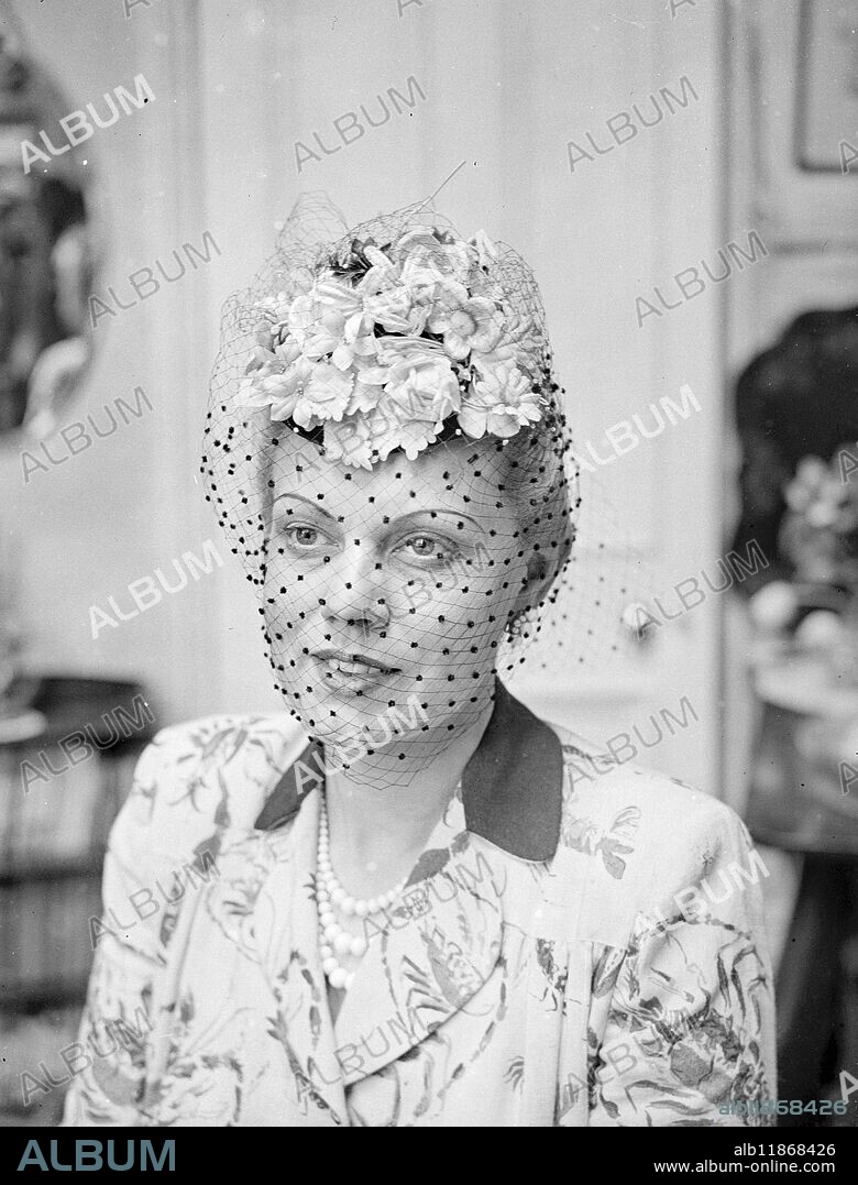 NOTE OF ORIGINALITY. Lovely opera singer Constance Shacklock , who is pictured here , remodels he own hats in between her singing performances . The wife of Mr . Eric Mitchell, repetiteur on the musical staff of the Covent Garden Opera Company , she is seen here wearing a delightful flowered toque ( roses , Violets and spring blossom) with a black veil , one of the hats she remodelled herself . 11 September 1949.