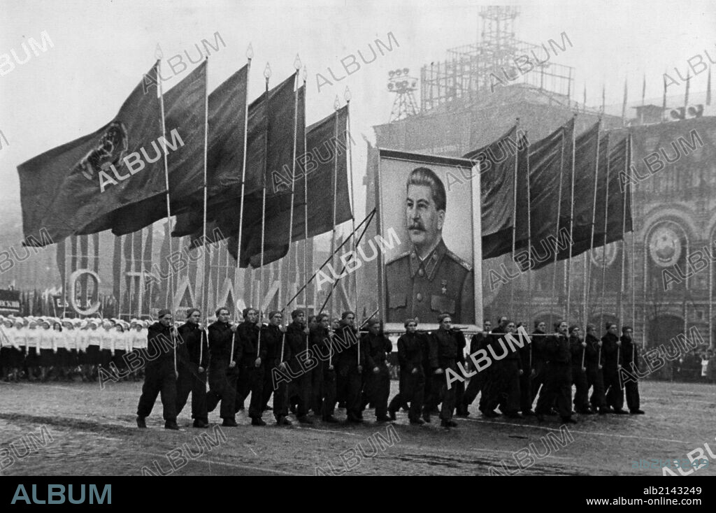A demonstration / parade of the working people in red square in moscow on november 7, 1950, the sportsmen are carrying soviet flags and an image of stalin.