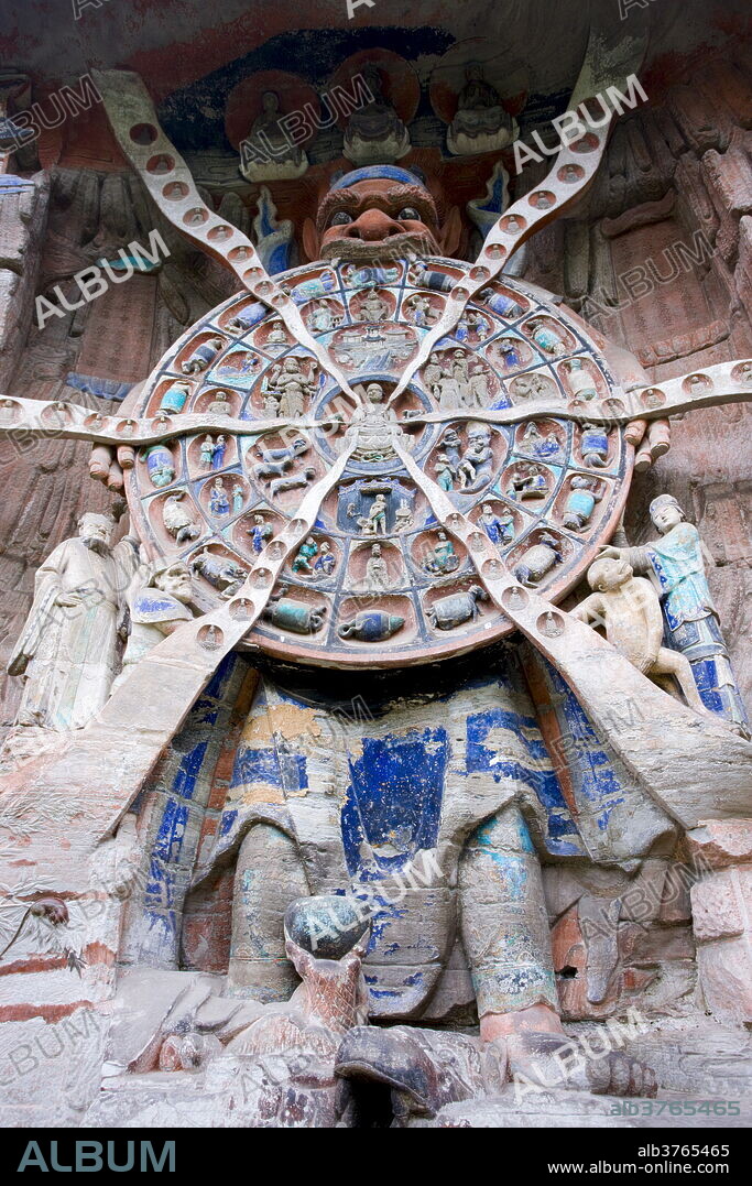 Anicca, God of Destiny holds wheel of life of Buddhist karma, Dazu rock carvings, Mount Baoding, China.