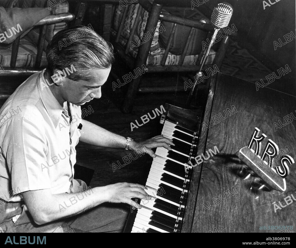 Frisch playing the piano at the British Mission Party, September 22nd, 1945. Otto Robert Frisch (October 1, 1904 - September 22, 1979) was a Jewish Austrian-British physicist. The rise of Hitler in 1933 made Frisch make the decision to move to London where he worked on cloud chamber technology and artificial radioactivity. He followed this with a five year stint in Copenhagen with Niels Bohr where he specialized in nuclear physics. With the outbreak of WWII he and Rudolf Peierls produced the Frisch-Peierls memorandum, which was the first document to set out a process by which an atomic explosion could be generated. This memorandum was the basis of British work on building an atomic device and also that of the Manhattan Project on which Frisch worked as part of the British delegation. At Los Alamos, one of his tasks was to accurately determine the exact amount of enriched uranium which would be required to create the critical mass. In 1946 he returned to England to take up the post of head of the nuclear physics division of the Atomic Energy Research Establishment and spent much of the next thirty years teaching at Cambridge. He died in 1979 at the age of 74.