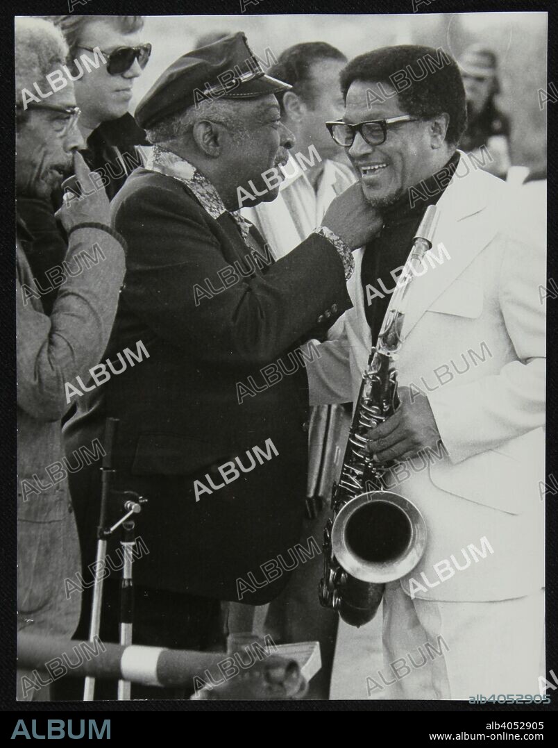 Count Basie chatting with Illinois Jacquet at the Capital Radio Jazz Festival, London, July 1979. Count Basie Orchestra drummer Butch Miles, wearing sunglasses, is in the background.