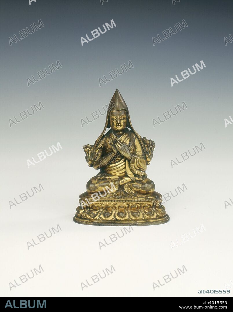 Gilt bronze Lama of the Yellow Hat sect, Tibet, 18th century. A gilt bronze Lama seated on a lotus petal base that extends two thirds of the way around the figure. The Lama is wearing the high pointed cap of the Yellow Hat sect, his hands are held together before him in the position to confer blessings. This figure probably represents the Lama Tsong Khapa - believed to be the third incarnation of Manjusri and regarded as the founder of the Geluk Order (Yellow Hat sect).