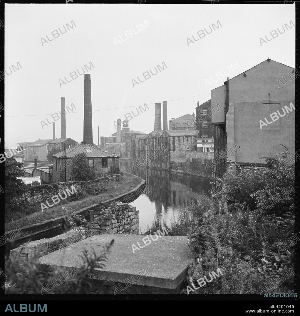 Weavers' Triangle, Burnley, Lancashire, 1966-1974. A view looking south-east along the Leeds and Liverpool Canal from Westgate Bridge showing mills and warehouses lining the canal and Clock Tower Mills in the distance.
