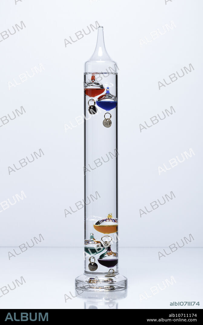 Galileo thermometer. Galileo thermometer is made of a sealed cylinder that contains a liquid (such as ethanol) and several small glass bulbs of varying density. Small metal tags are attached to individual bulbs to adjust their respective densities and are also used for reading the temperature. The bulbs are often filled with colored liquids for decoration. The density of the surrounding liquid in the cylinder changes with changing temperature. This causes the submerged bulbs to rise or sink depending on their individual densities. The temperature is then read on the tag of the lowest floating bulb.