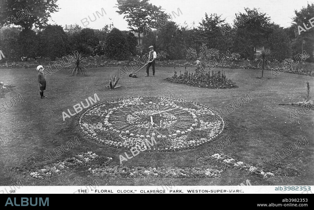 Floral clock, Clarence Park, Weston-super-Mare, Somerset, 1913. Floral clocks were a popular exhibit in municipal gardens. A gardener uses a small push mower to cut the extensive lawn.