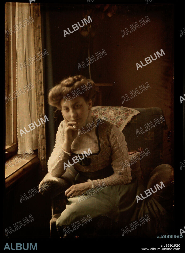Woman sitting by window, Interior with young woman sitting by window., Johannes Hendrikus Antonius Maria Lutz, 1907 - 1916, glass, height 90 mm × width 120 mm.