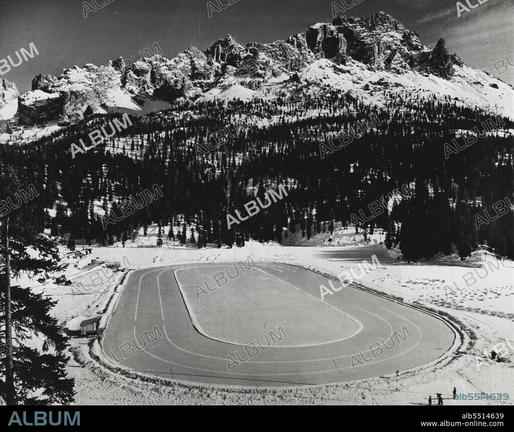Expecting Company (First Of Seven) -- This is the speed skating rink on frozen Lake Misurina, near Cortina D'Ampezzo, site of the 1956 Winter Olympic Games. The jagged Dolomites form a backdrop. A second highway is being constructed between Misurina and Cortina to help traffic flow smoothly.Cortina, a village of 8,000, experts a housing problem when an estimated 200,000 sports enthusiasts descend upon the area next February. The people of Cortina are really looking forward to the big event -- though they estimate they will be able to handle but a fourth of the crowd. The rest of the fans will have to find accommodations in other towns in the area. August 19, 1955. (Photo by United Press).