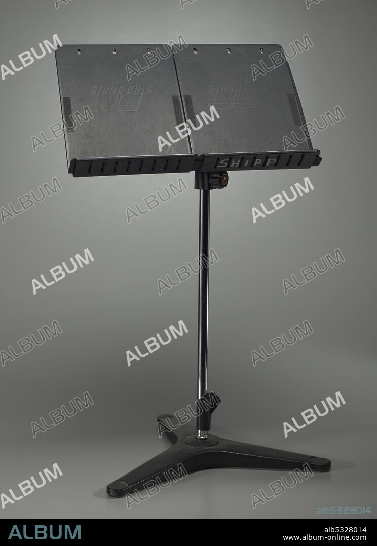 A black, metal music stand owned by African-American musician Ginger Smock. The stand has a metal tripod base and an adjustable music support with a small shelf. Embossed on the back of the support is the Belmonte company logo. Plastic extensions are screwed to the metal support above the shelf. Embossed on each side of the extension on top is “SNAP-OUTS.” The base and support is connected with an adjustable central pole with locking screws. Written in white paint on the bottom of the base is “GINGER” and “SHIPP.” Written in white paint on the shelf of the support is “SHIPP.”.