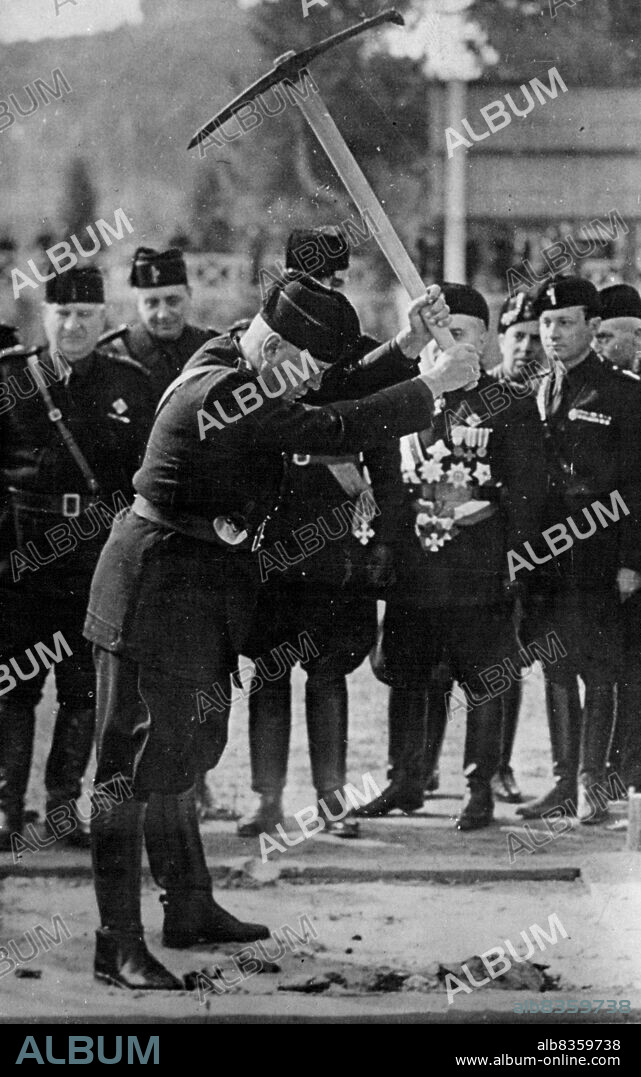 Mussolini Weilds A Pick Axe - Mussolini using the pick ace during the ceremony watched by General Starace, (holding shovel) and other Fasoist officials.In celebration of the 15th anniversary of the March on Rome, Mussolini addressed 100, 000 ***** officials at the Mussolini Forum, in Rome. After this ceremony the Duce used a pick axe to start the work of ***** erection of the House of Littorio at the Forum. October 30, 1937. (Photo by Keystone).