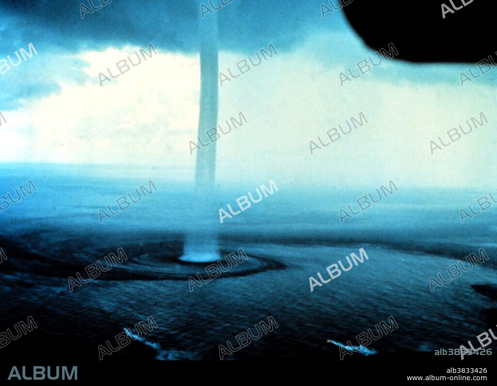 A waterspout off the Florida Keys photographed from an aircraft. Florida, September 10, 1969.  A waterspout is a tornado occurring over water that forms a column of water and mist extending between the surface and the clouds above. Waterspouts have a five-part life cycle: formation of a dark spot on the water surface, spiral pattern on the water surface, formation of a spray ring, development of the visible condensation funnel, and ultimately decay.