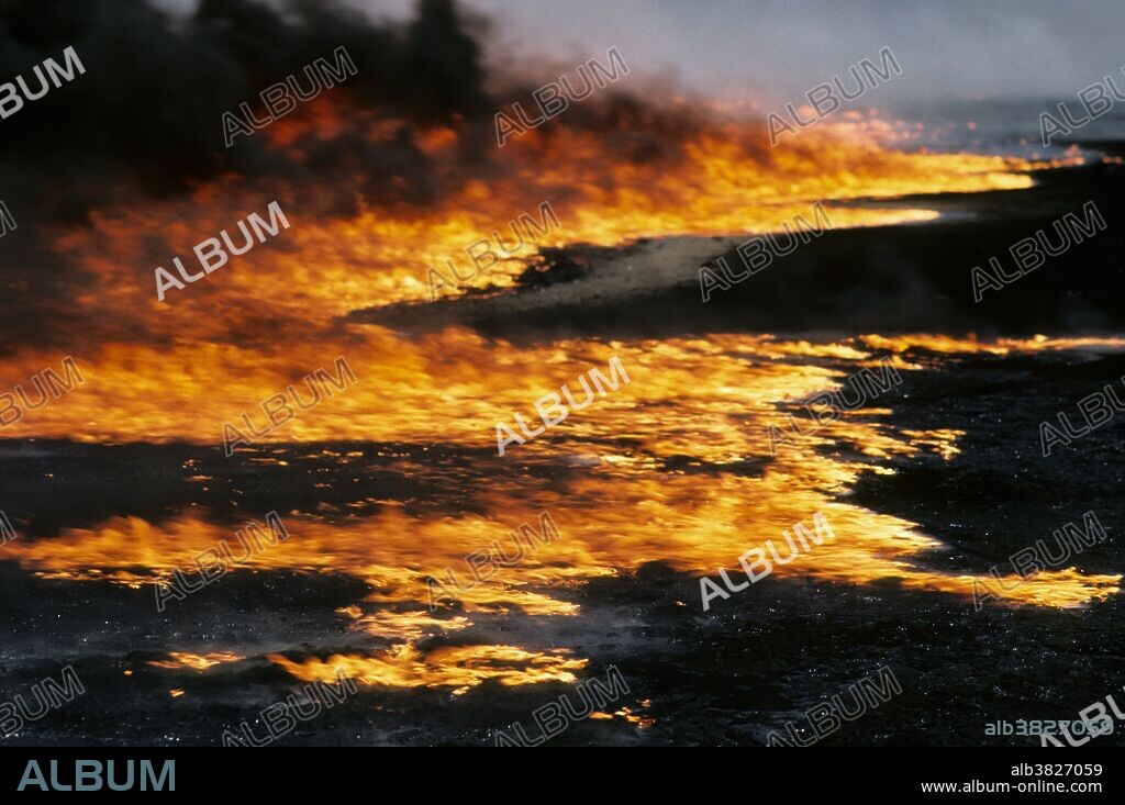 Kuwait City, Kuwait; March 1991. Oil wells burning out of control in the Al-Ahmadi oil fields located on the outskirts of Kuwait City. The oil fields were set on fire by retreating Iraqi troops hoping to create some cover from American airplanes strafing their positions. The fires and smoke caused one of the greatest environmental disasters of modern times. Nearly 800 oil wells were set ablaze by the retreating Iraqi army and the fires were not fully extinguished until November 6, 1991, eight months after the end of the war. The fires consumed an estimated six million barrels of oil daily. Their immediate consequence was a dramatic decrease in air quality, causing respiratory problems for many Kuwaitis. The sabotage of the oil wells also impacted the desert environment, which has a limited natural cleansing ability. Un-ignited oil from the wells formed about 300 oil lakes that contaminated around 40 million tons of sand and earth.
