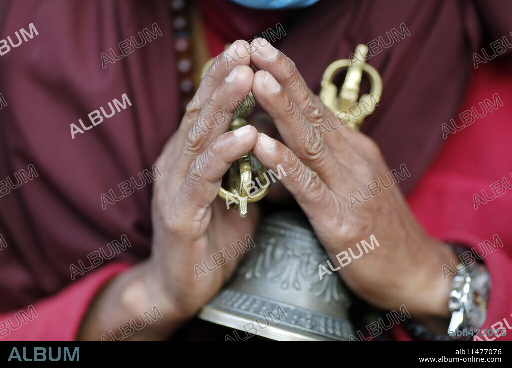 Buddhist monk (lama) in traditional robes holding ritual attributes of Buddhism, rosary, vajra, bell, Pema Osel Ling Monastery, Kathmandu, Nepal, Asia.