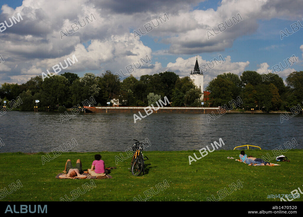 PARQUE TREPTOWER. Personas estiradas en el césped, junto al río Spree. Berlín. Alemania.
