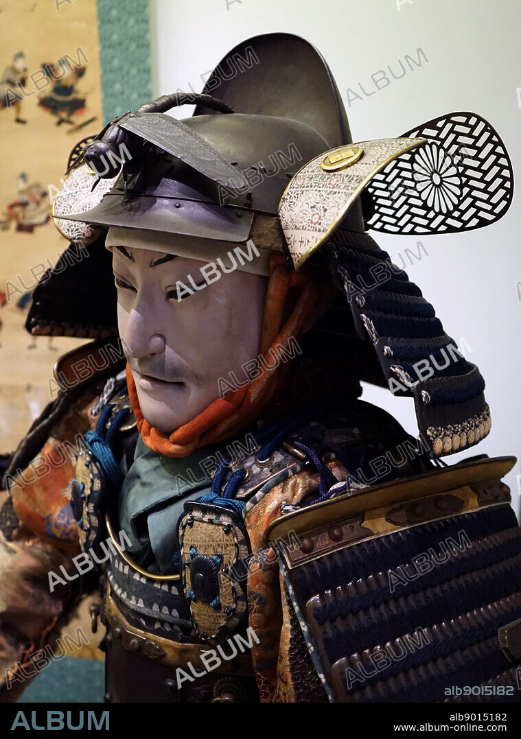 Japanese figure of a samurai dressed in armour. Suit of armour about 1800; made from: iron, gilded and patinated copper alloy, leather, lacquer and silk Figure: wood, gesso, glass and human hair. lacquered wood.