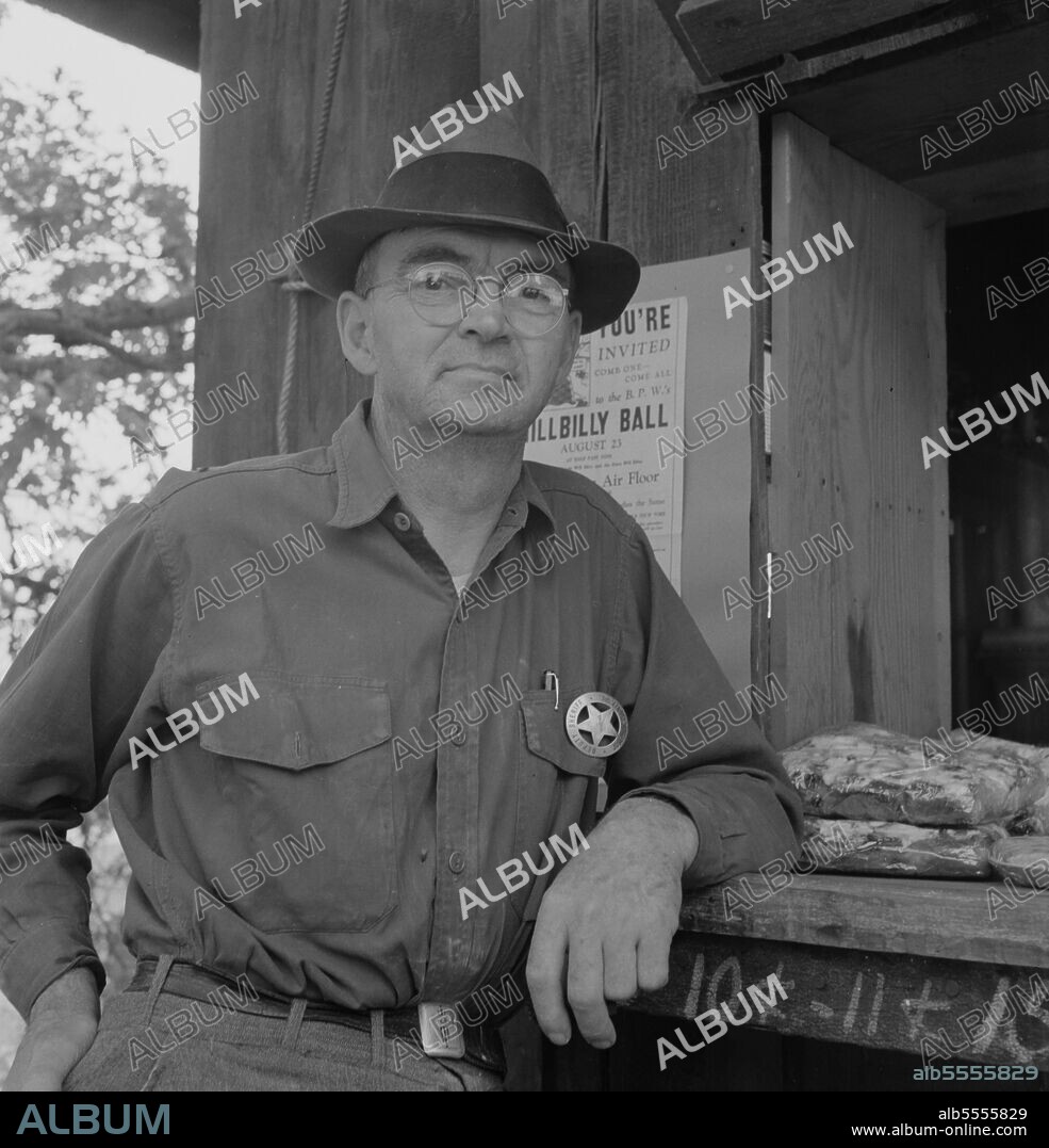 DOROTHEA LANGE. Oregon. Josephine County, near Grants Pass. Deputy sheriff, stationed at paymaster's window on large Williamette hop ranch. Owner employs between 500 and 600 hop pickers for three weeks each year. He says, "We have (meaning deputy) to kinda keep them scared as much as anything".