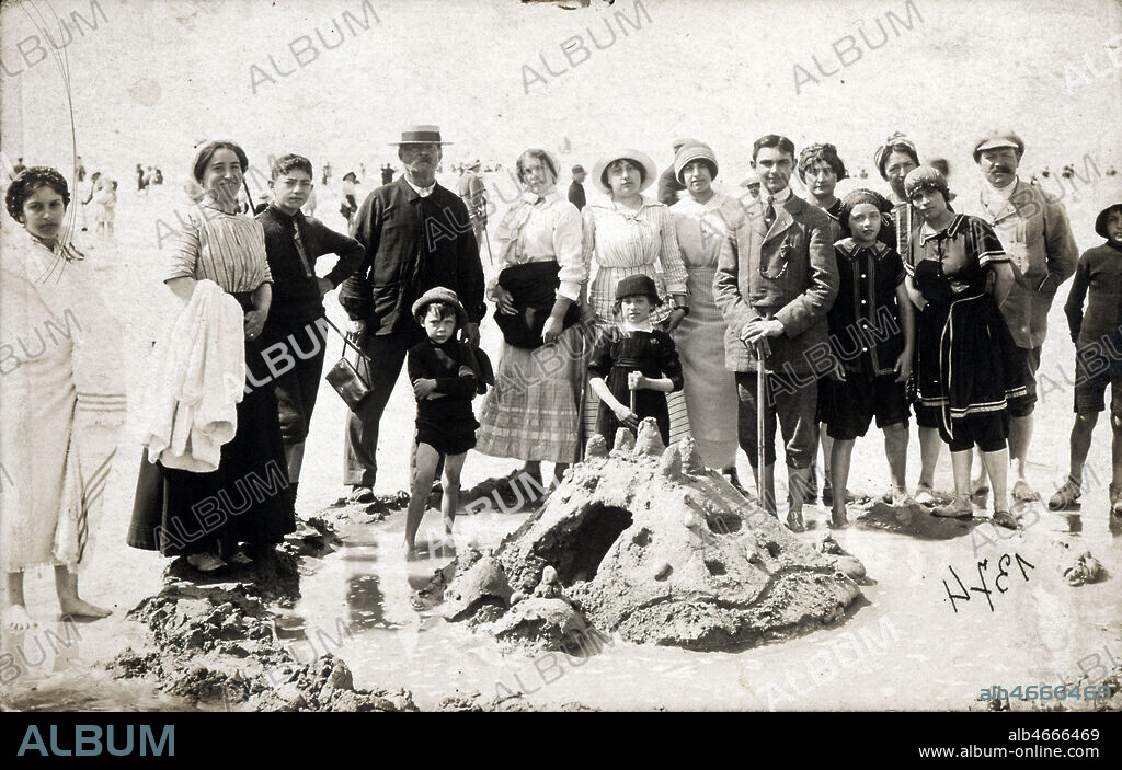 Famille derriere un chateau de sable sur la plage deTreport en Normandie. Carte postale editee vers 1910-1914. Credit : Collection KHARBINE-TAPABOR.