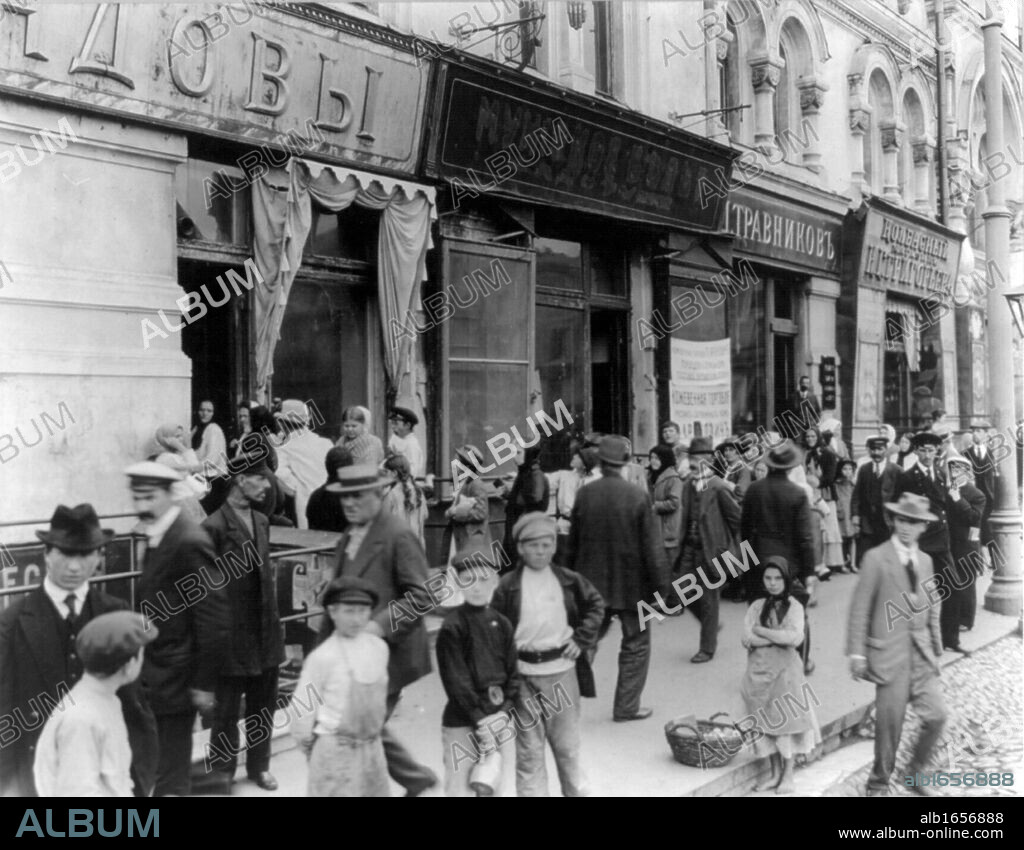 Russian street scene, February 1918: Women and children wait in a long line to buy milk. A girl is selling apples.