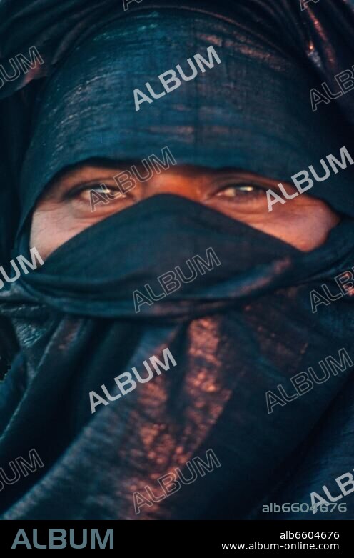 1980, Algerie, Sahara, Hoggar, les Kel Ahaggar ou Touareg. Oued Tin Tarabin, ceremonie d'un mariage chez les Ayt Lowayen, cet homme a revetu son turban en tissu indigo, fabrique a Kano ( capitale du Pays Haoussa, au Nigeria ).// 1980, Algeria, Sahara, Hoggar, Kel Ahaggar or Tuareg. Oued Tin Tarabin, a wedding ceremony in Ayt Lowayen tribe, this man has put his t.