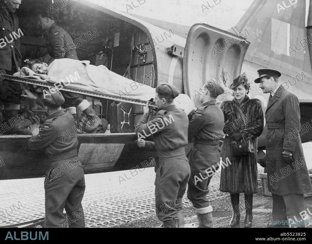 Duchess of Kent Visits West Country Aerodrome -- The Duchess of Kent (right) watches a stretcher case being taken out of a hospital plane.The Duchess of Kent visited a West Country aerodrome where she witnessed the arrival of wounded soldiers, who had been flown over from the Belgian Theatre of War. Since D-Day, R.A.F. Transport Command has flown 50,000 casualties to hospitals in England. December 8, 1944.